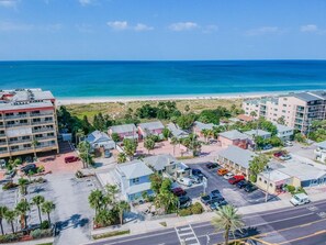 An aerial view of a coastal area with buildings, a parking lot, and a beach.