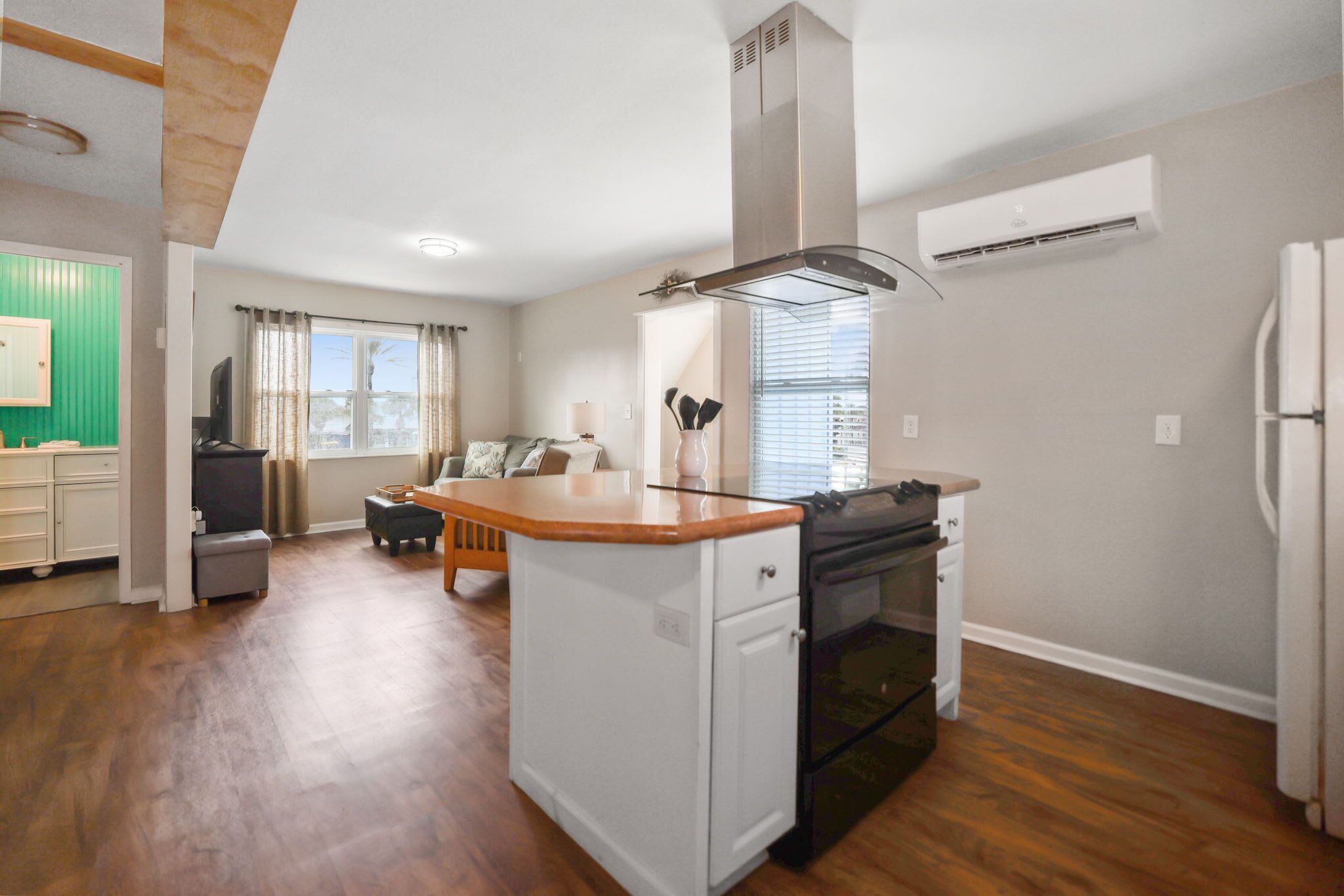 A modern kitchen with a central island, built-in oven, and a large window.