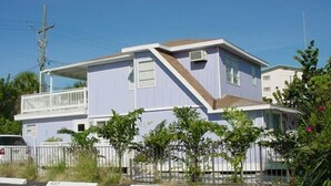 A two-story residential building with a balcony on the upper floor, surrounded by greenery. - Studio by the Sand  & Johns Pass (Madeira Beach)