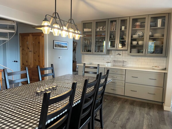A kitchen with a checkered table, wooden chairs, and cabinets with glass doors.