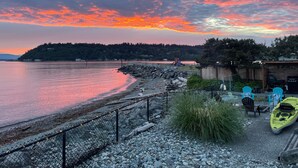 A waterfront property with a rocky shoreline, a kayak, and a barbecue area.