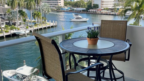 A balcony with a round table and chairs, overlooking a marina with boats and a cityscape in the background. - South Florida's Intercoastal Waterway (Pompano Beach)