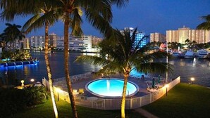 A circular pool with a fountain, surrounded by palm trees and a waterfront view of buildings. - South Florida's Intercoastal Waterway (Pompano Beach)