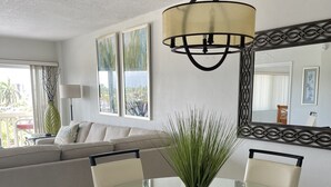 A dining area with a glass table and chairs, a hanging light fixture, a sofa, and a large window with a view. - South Florida's Intercoastal Waterway (Pompano Beach)