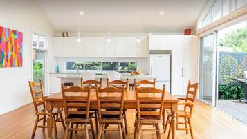 A modern kitchen with white cabinets, a central island, and a dining area with wooden chairs and a table.