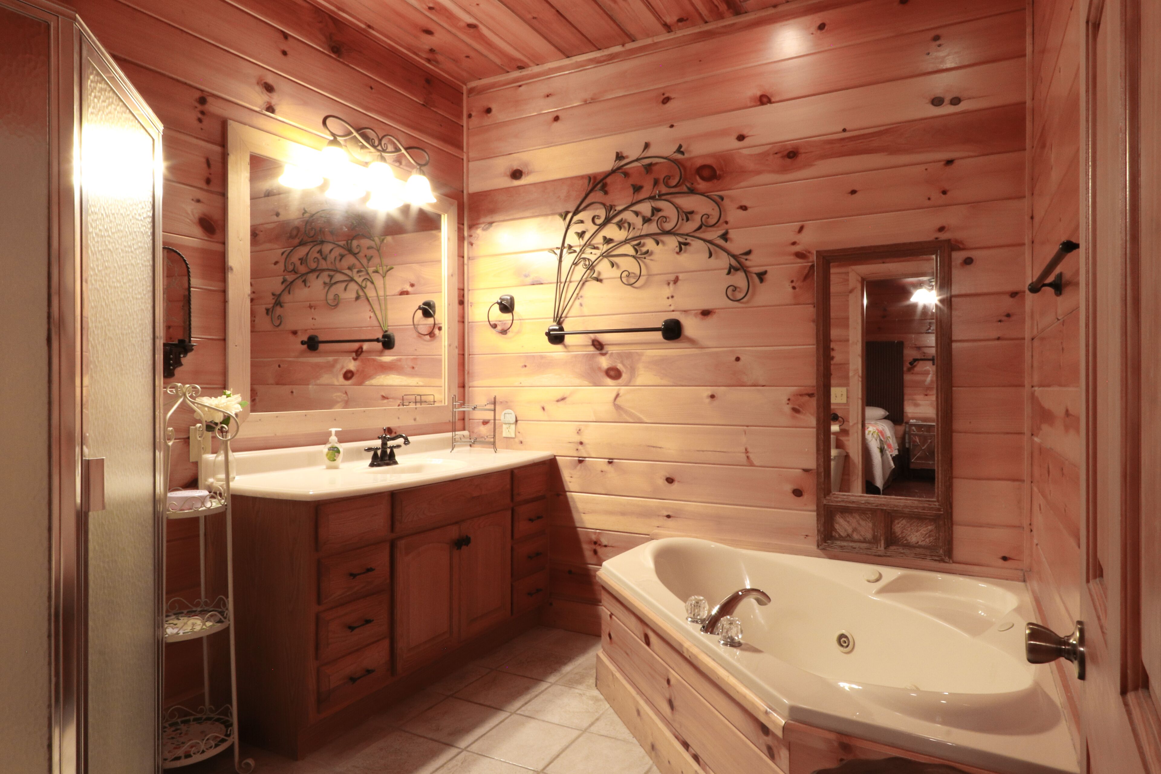 A wooden cabin bathroom with a large sink, vanity, and bathtub.