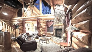 A log cabin interior with a fireplace, leather sofa, and rustic decor. - Business wifi, privacy, luxury, creek, firepit, theater, comfort and unique
(Pigeon Forge)