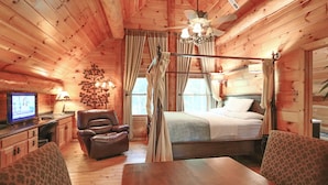 Habitación de cabaña de madera con una cama, televisor, sillón de cuero y una mesa de comedor.