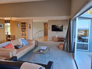 A living room with a sofa, coffee table, and a TV. There's a sliding glass door leading to an outdoor area.