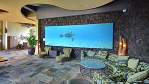 Eine geräumige Lobby mit einer großen Aquariumwand, bequemen Sitzgelegenheiten und einem Steinboden.