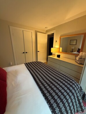 A hotel room with a bed, a dresser, a mirror, and a lamp.