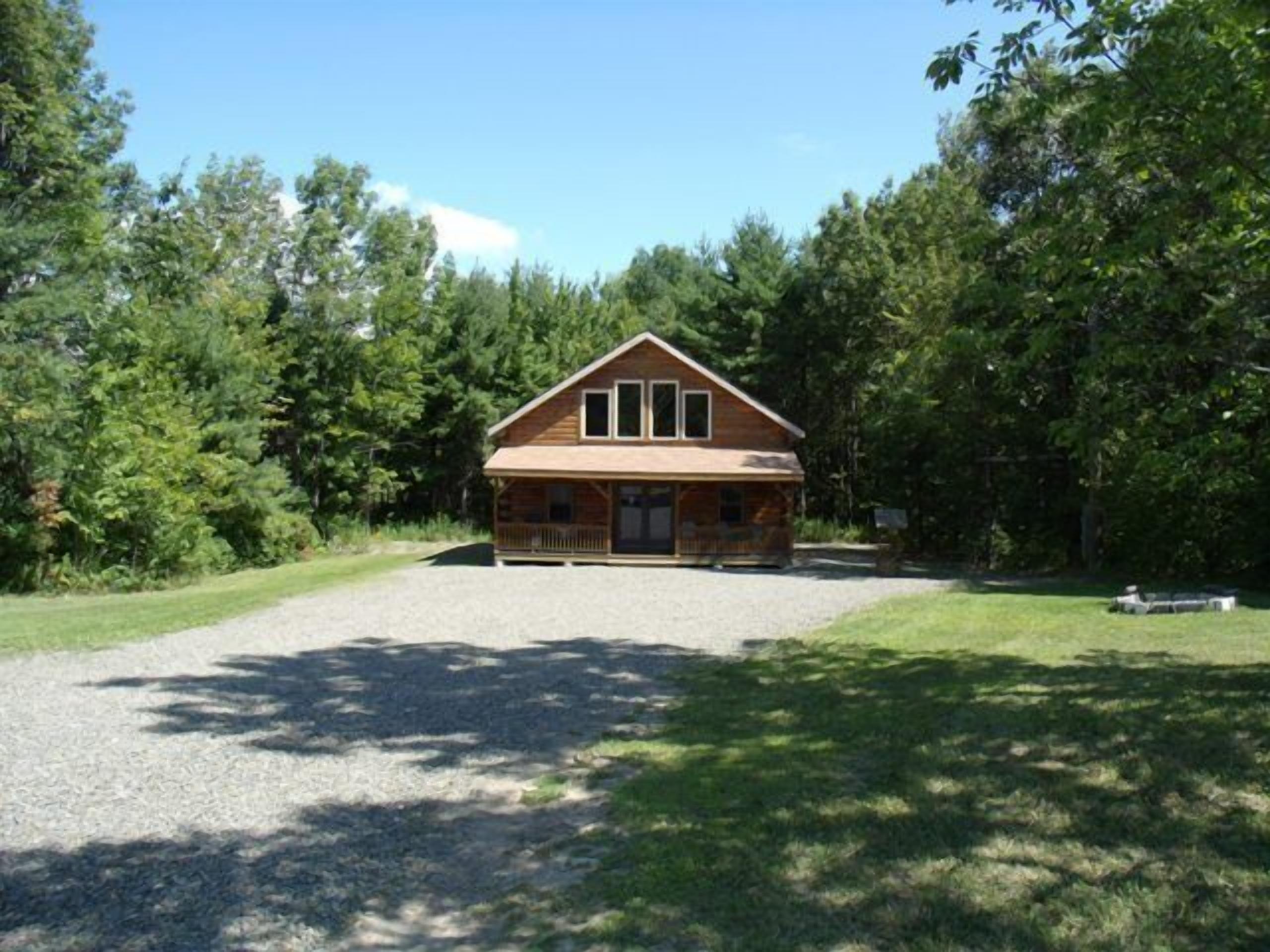 Une cabane en bois avec un porche, entourée d’arbres.