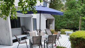 Une terrasse en bois avec des meubles d’extérieur, un espace salon couvert et une plante en pot.