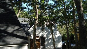 Un bâtiment blanc avec un toit en pente, entouré d’arbres.