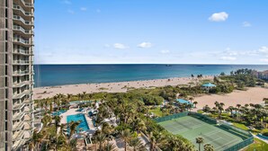 Un hotel de gran altura con vista al mar, piscina y canchas de tenis.