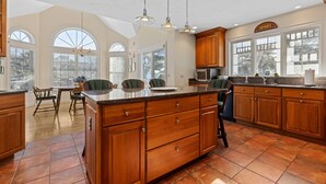 A spacious kitchen with wooden cabinets, a large island, and a dining area with chairs. - Chatham-Walk to Town/Beach-Multi Family Friendly (Chatham)