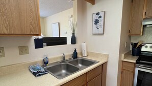 Une cuisine avec des meubles en bois, un évier en acier inoxydable, une cuisinière et un tapis rayé noir et blanc.