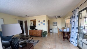 Un grand salon comprenant une table à manger, un téléviseur et un ventilateur de plafond.