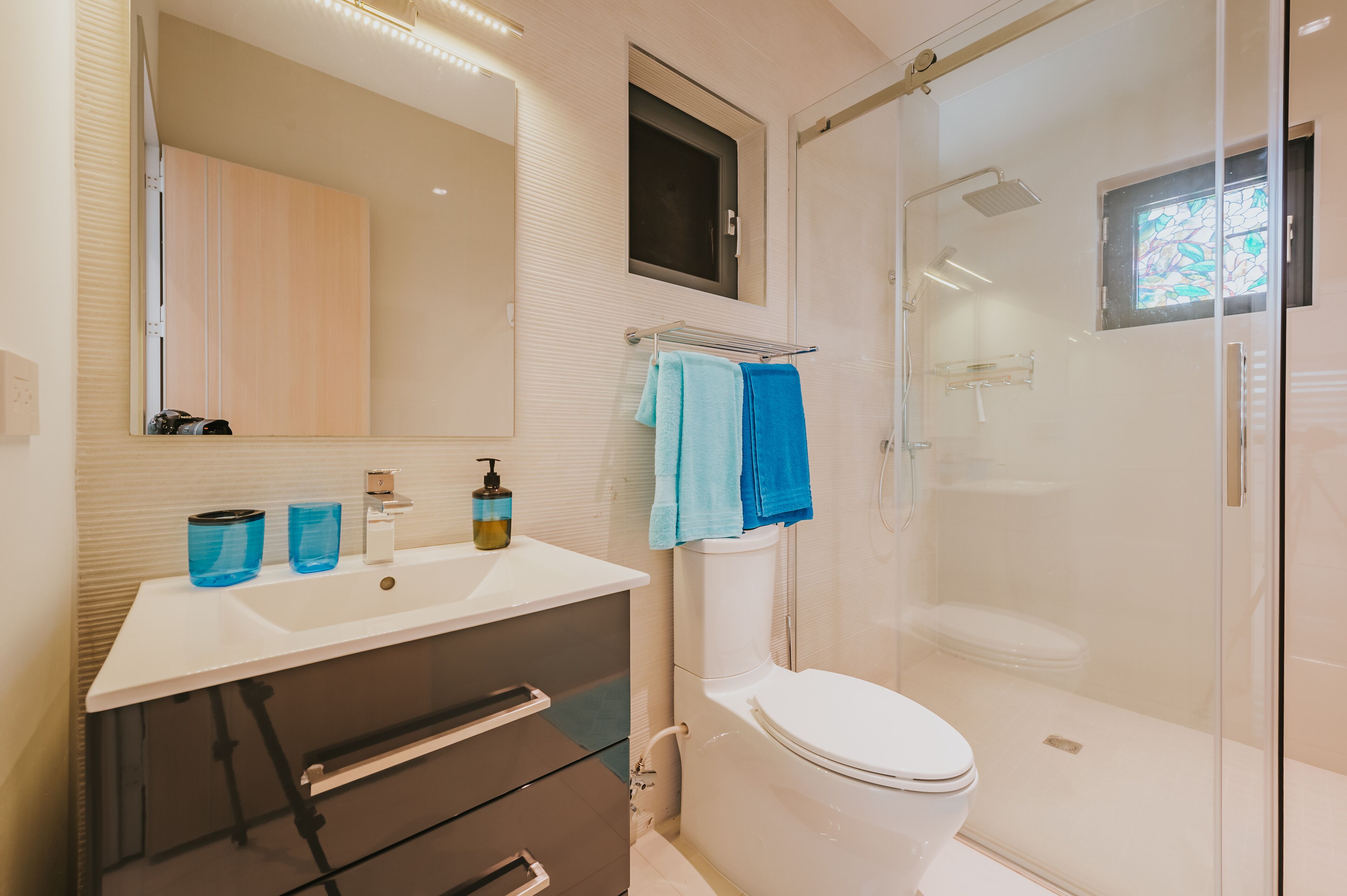 A modern bathroom with a white sink, a toilet, and a glass-enclosed shower.