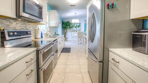 Una cocina moderna con electrodomésticos de acero inoxidable, armarios blancos y salpicadero de azulejos.