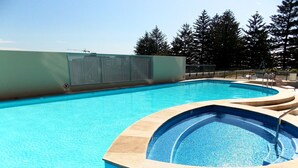 Una piscina con borde curvo y zona de solárium con baldosas.