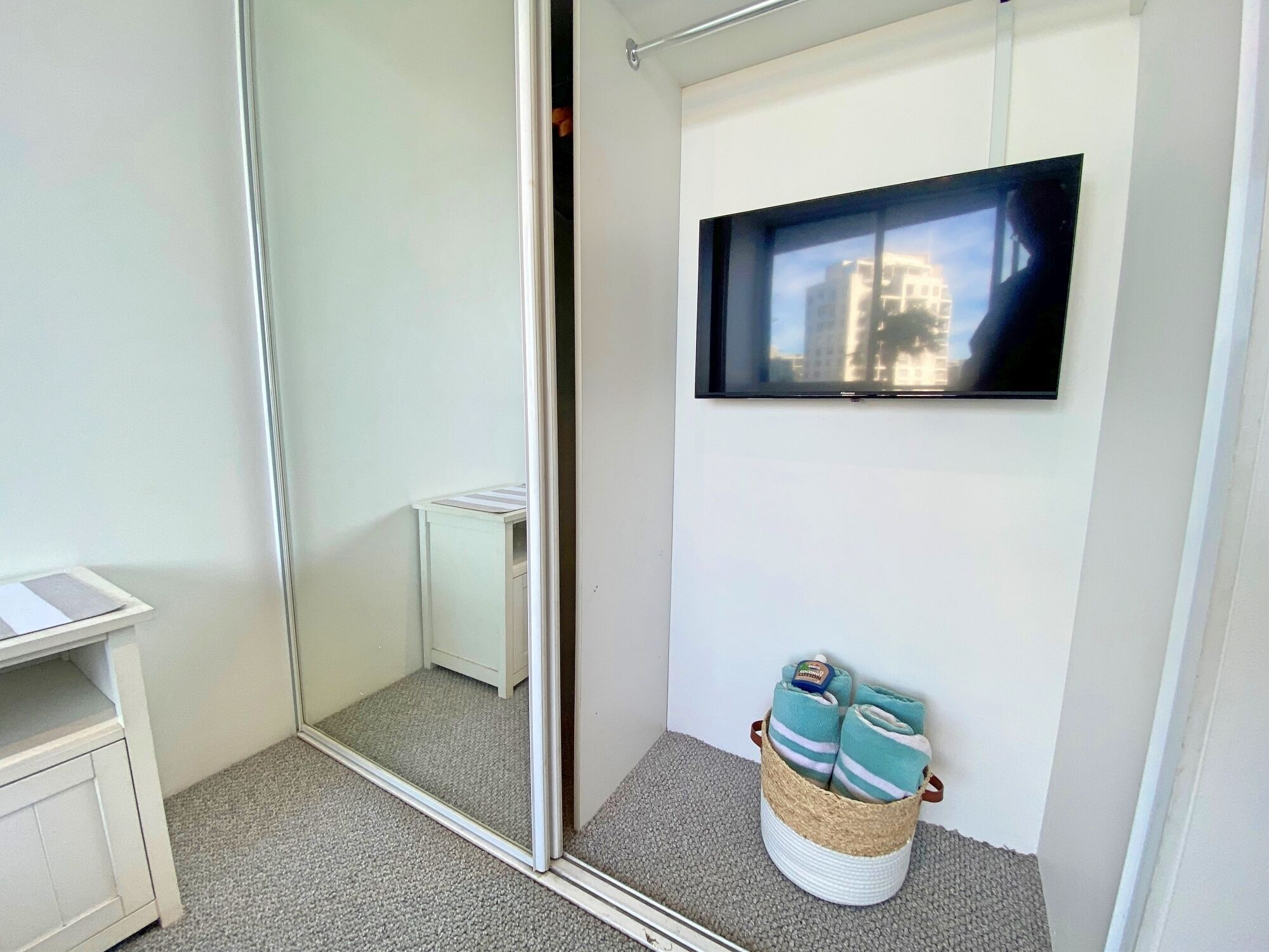 A small, modern bathroom with a large mirror, a toilet, a sink, and a TV mounted on the wall.