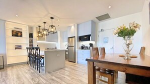 Una cocina moderna con una isla central, taburetes de bar e iluminación colgante.