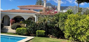 A Mediterranean-style villa with a swimming pool, lush garden, and mountain backdrop. - Luxury bright villa in Marbella Golden Mile with great sea and mountain views (marbella)