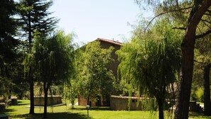 A courtyard with a stone building, trees, and a grassy area. - Typical house with large pool and lovely views (Cortona)