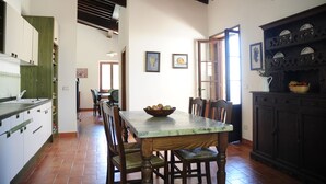 A dining area with a wooden table and chairs, a bowl of fruit, and a dark cabinet with decorative plates. - Typical house with large pool and lovely views (Cortona)