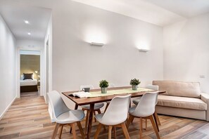 Enjoy meals in this dining area with a table for four, surrounded by potted plants and a comfortable sofa.