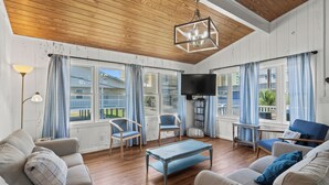 Un salon avec un plancher en bois, un téléviseur et deux canapés avec des coussins.