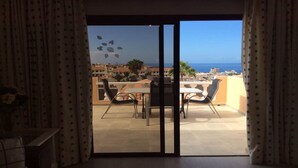 A balcony with a table and chairs, a view of the sea, and a cityscape in the background. - Apartment with Large Sunny Balcony with stunning views (Adeje)