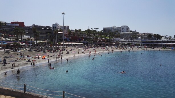 A crowded beach with clear blue water, umbrellas, and people enjoying the sun. - Apartment with Large Sunny Balcony with stunning views (Adeje)