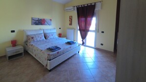 A bedroom with a bed, nightstand, and a window with curtains. - La Mansarda Carbonia It (Carbonia)