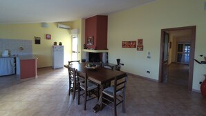 A spacious kitchen with a dining area, featuring a large wooden table and chairs, a refrigerator, and a tiled floor. - La Mansarda Carbonia It (Carbonia)