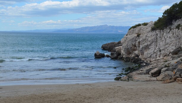 Ein Strand mit felsigen Klippen und ruhiger See.