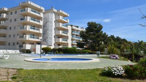 Ein modernes Apartmenthaus mit Balkonen, einem Schwimmbad und angelegten Gärten.