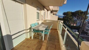 Ein Balkon mit Tisch und Stühlen, gefliestem Boden und Blick auf die Stadt.