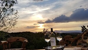 A table with two wine glasses and bottles, set against a scenic sunset view. - SANTA FE ADOBE JEWEL (Santa Fe)