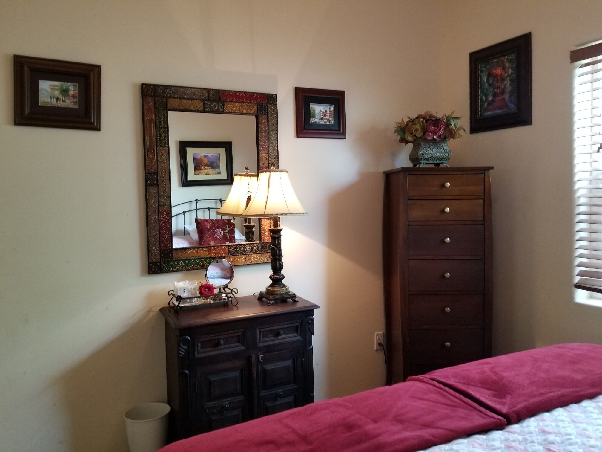 Un dormitorio con cama, cómoda, espejo, lámpara y decoración en la pared.