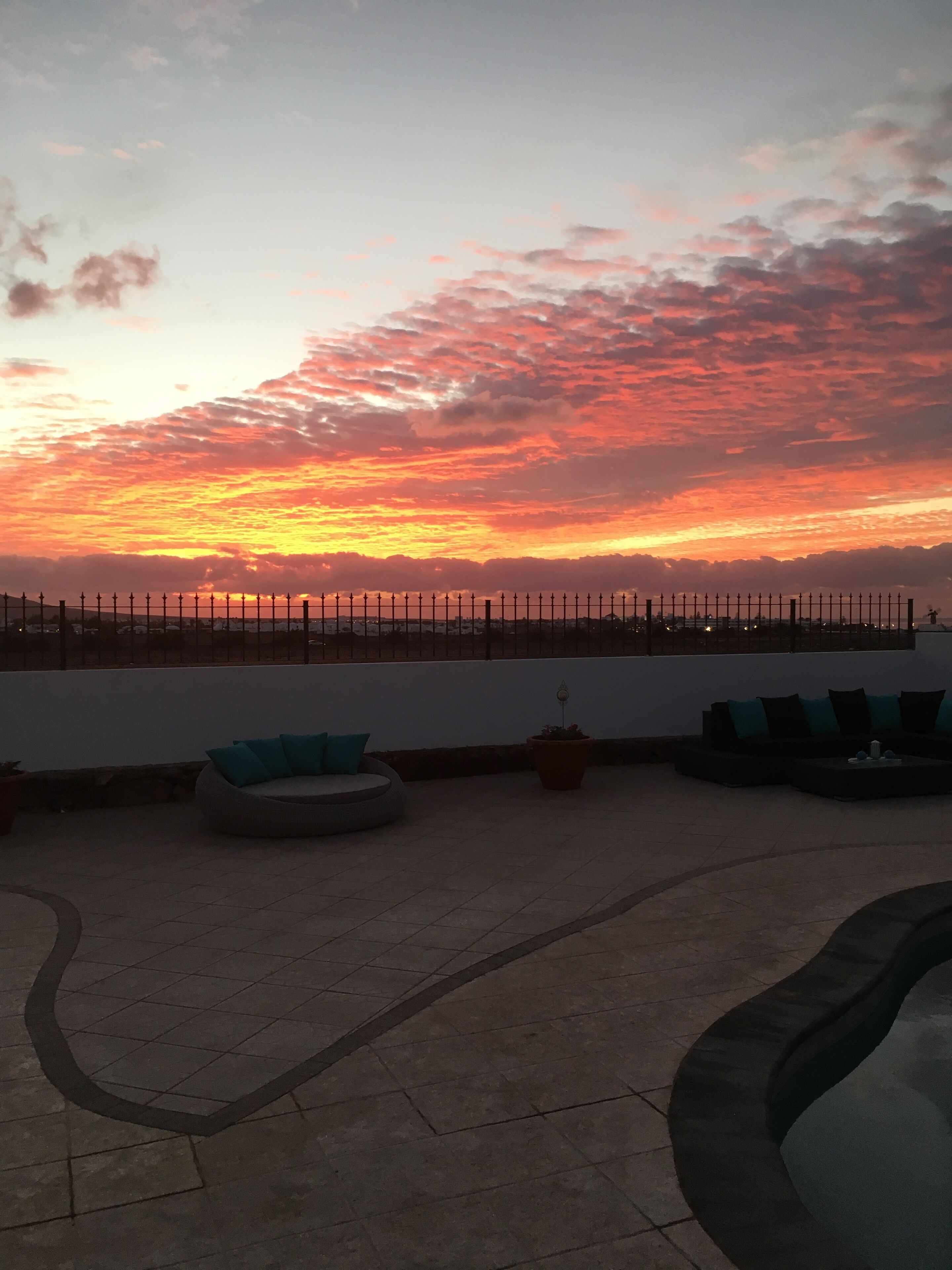 Eine Dachterrasse mit Sitzgelegenheiten im Freien und Blick auf den Sonnenuntergang.