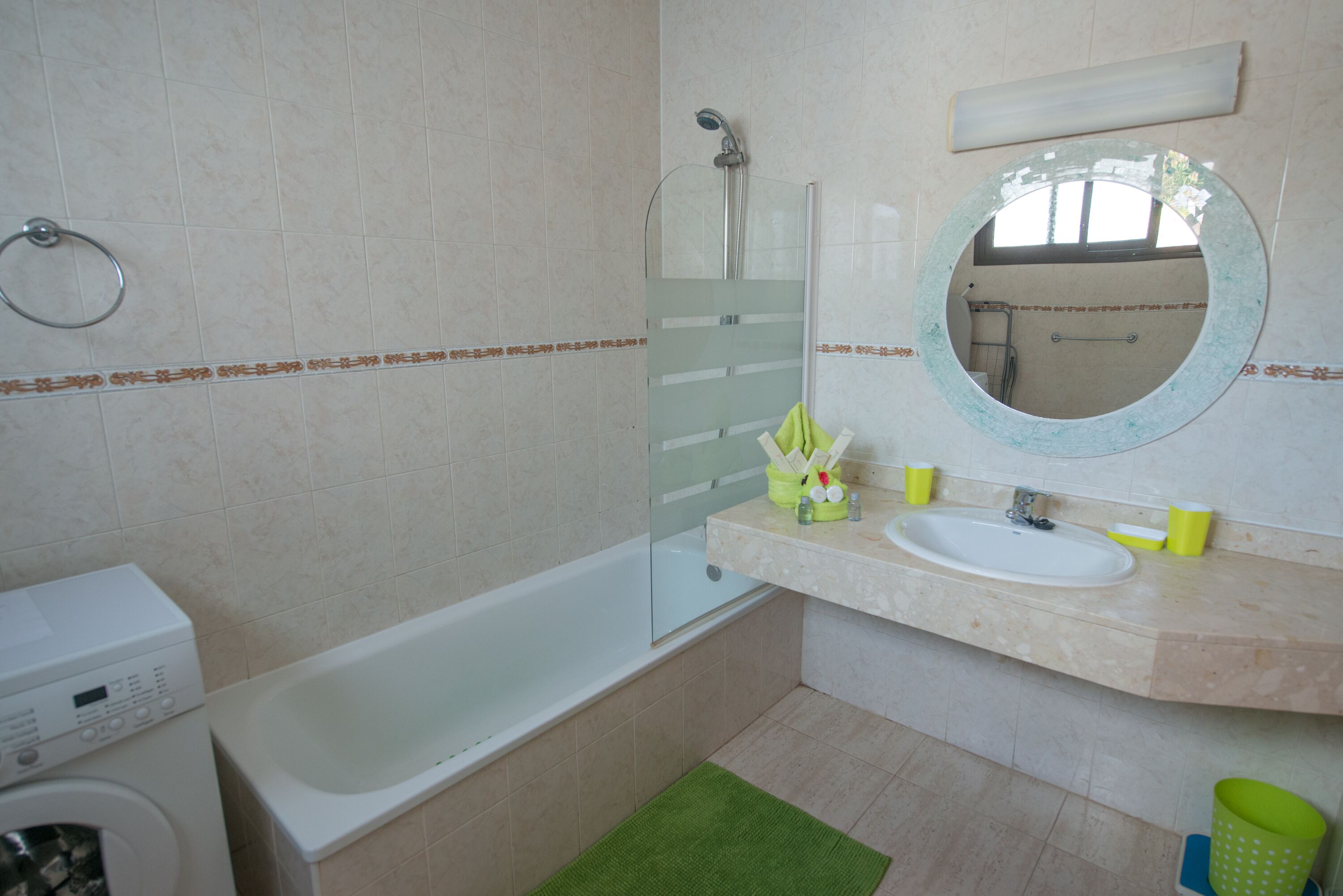 A bathroom with a bathtub, a sink, a mirror, and a washing machine.