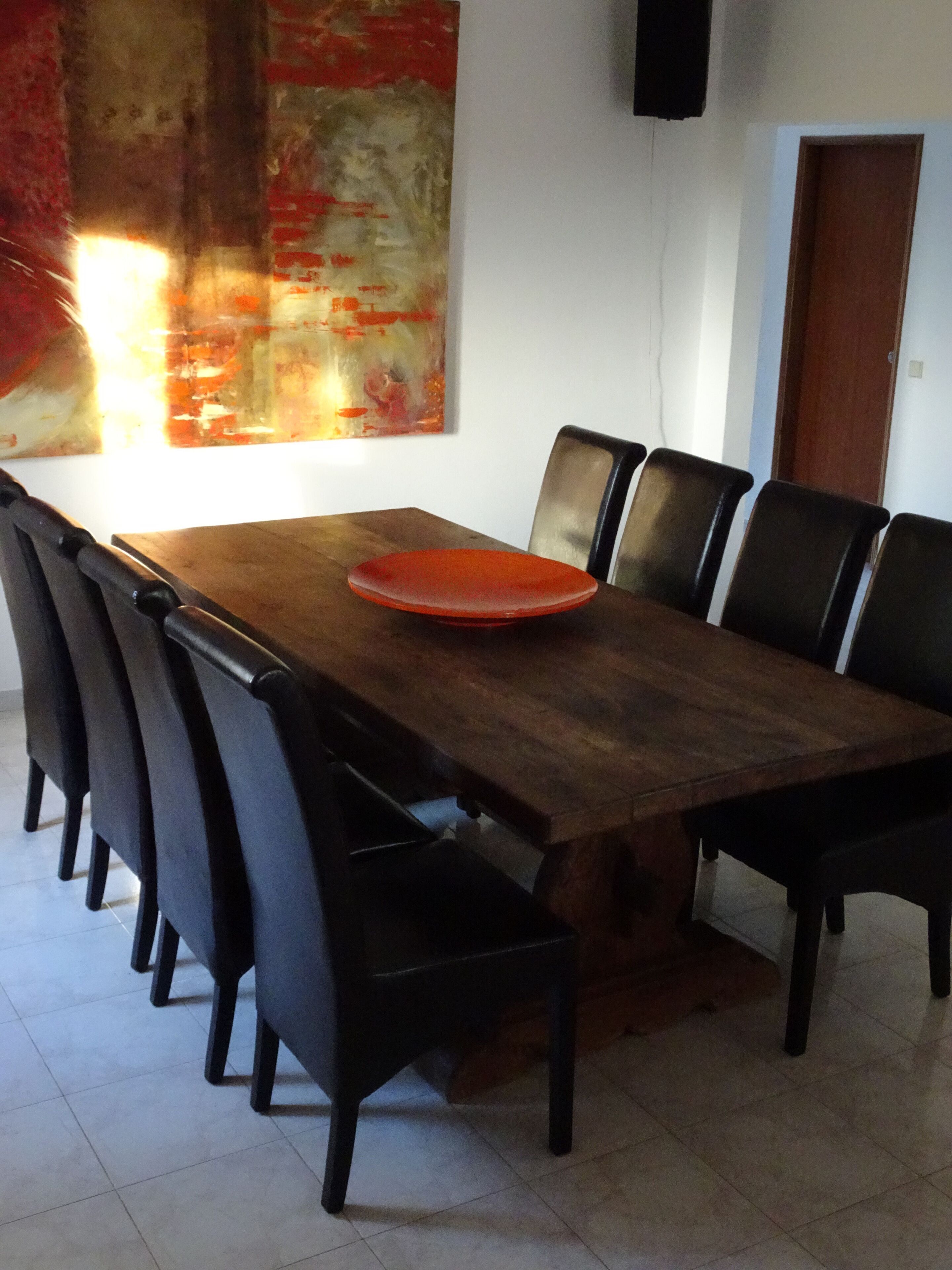 Un'area pranzo con un tavolo di legno, sedie nere e un piatto rosso.