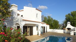A white villa with a swimming pool, surrounded by lush greenery and flowering plants. - Large Villa with own Pool, 4 Bedrooms, Family Friendly, Shaded Pavillion. (Vale Covo, Loule)
