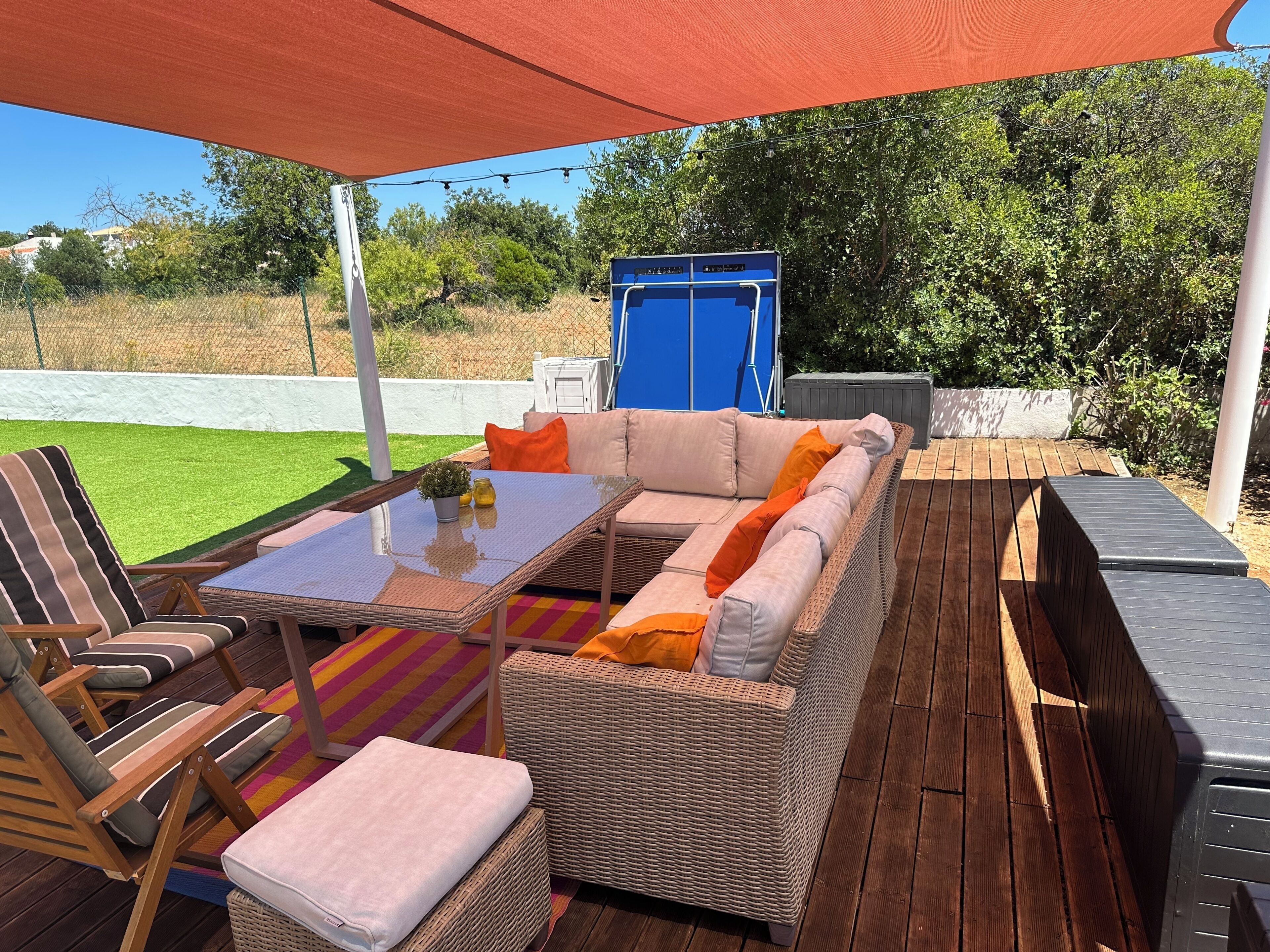 An outdoor seating area with wicker furniture, a table, and a blue door in the background.