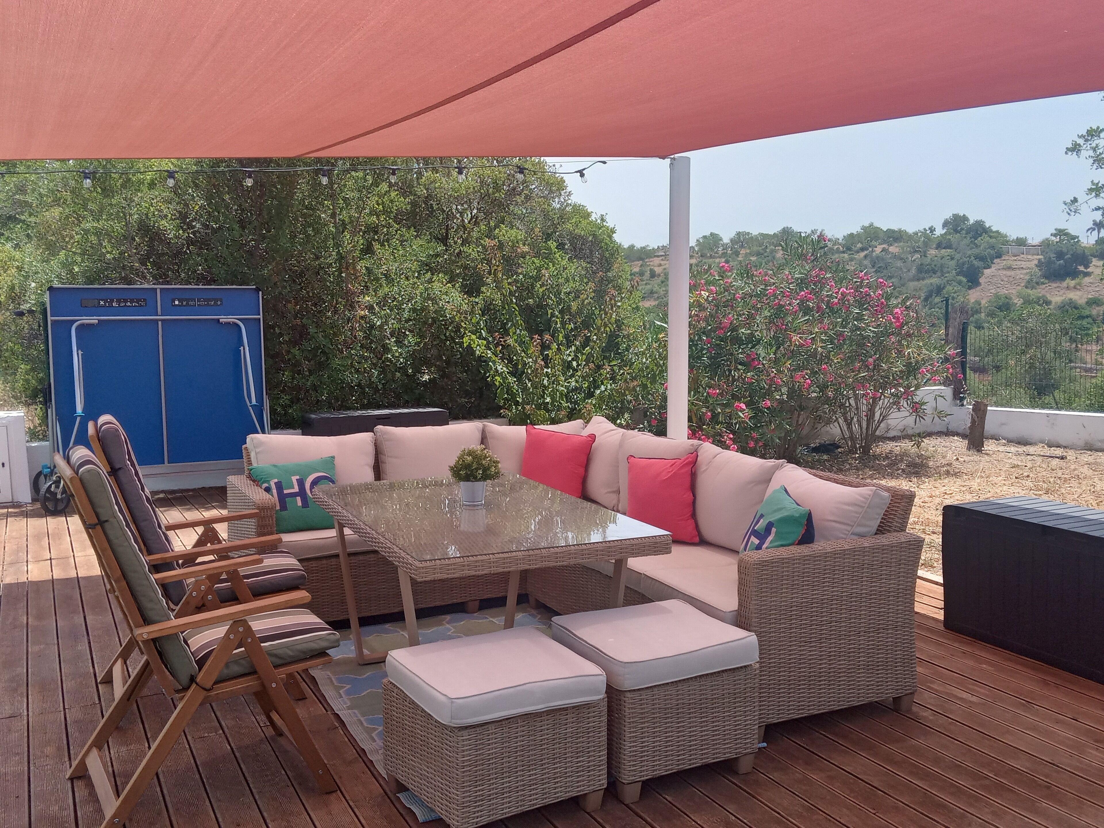 An outdoor patio with wicker furniture, a glass table, and a blue cabinet.