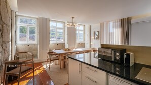 A kitchen with a wooden island, white cabinets, and a black countertop. - Feel Porto Ribeira Vintage Duplex (Oporto)