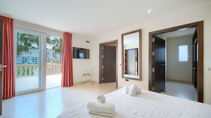 A hotel room with a large bed, a TV, a sliding glass door to a balcony, and a mirror. - #Luxury 4 Bed Villa, Heated Pool, Cinema, Gym, Sauna, Squash Court (La Cala)