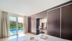 A modern hotel room with a large bed, a desk, and a view of a swimming pool. - #Luxury 4 Bed Villa, Heated Pool, Cinema, Gym, Sauna, Squash Court (La Cala)